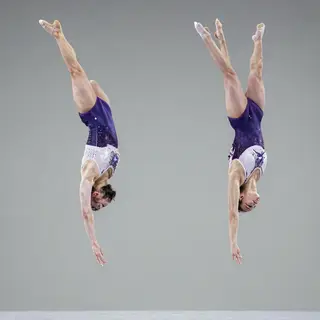 Two gymnasts performing a synchronized handstand, side by si