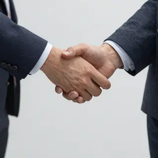 Two people shaking hands in a professional setting, all fing