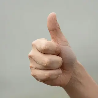 A hand giving a thumbs-up with four fingers curled and thumb