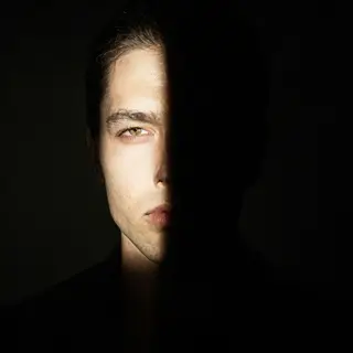 A portrait with dramatic split lighting — half the face brig