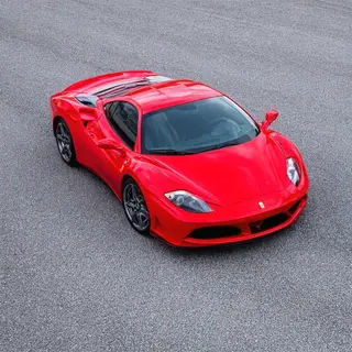 A bright red sports car parked on a gray asphalt road — the 