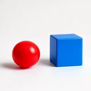A red ball and a blue cube sitting side by side on a white s
