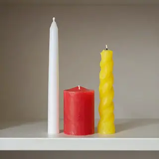 A tall thin white candle, a short fat red candle, and a medi