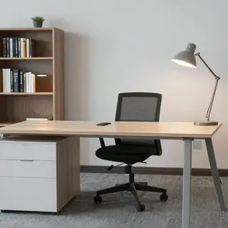 An office workspace with a desk, chair, bookshelf, and lamp 