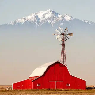 A landscape with a red barn in the foreground at large scale