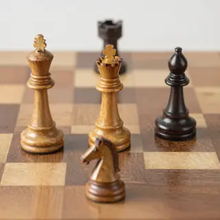 Five chess pieces on a board: a king in the center, a queen 