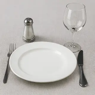 A dinner table scene with a plate, fork, knife, wine glass, 
