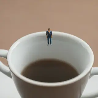 A tiny person standing on the rim of a coffee cup, looking d