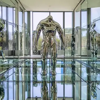 A chrome sculpture in a room with a glass floor and large wi