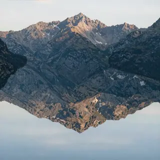 A mountain range reflected in a still alpine lake, with the 