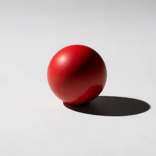 A red sphere on a white surface with a single shadow cast to