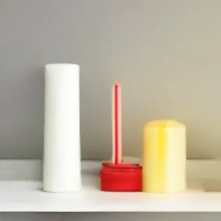 A tall thin white candle, a short fat red candle, and a medi