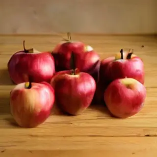 Exactly 3 red apples arranged on a wooden table