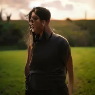 A person standing outdoors at midday with a short shadow dir