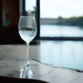 A crystal wine glass on a polished marble counter next to a 