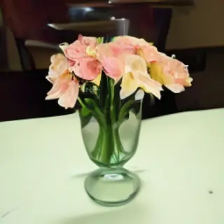 A vase of flowers on a glass table with a clear reflection v
