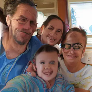 A family photo with four people: a father beaming with pride