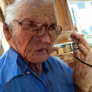 An elderly man in his 70s with age spots and thinning gray h