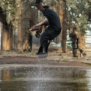 A man captured mid-jump over a puddle, body in the air with 
