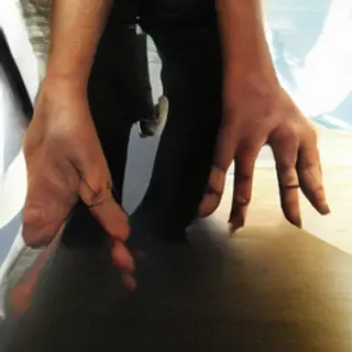 A person standing with both hands visible at their sides, fi