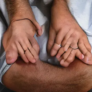 A man with arms crossed, both hands resting on opposite uppe