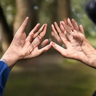 Two people doing a high-five, palms meeting with all fingers