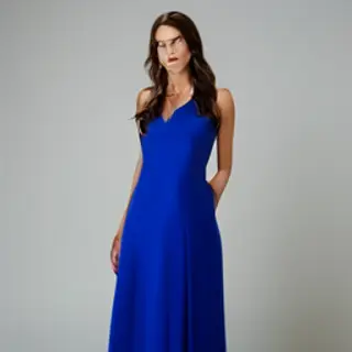 A woman wearing a royal blue evening dress against a neutral