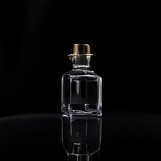 A clear glass perfume bottle on a reflective black surface w