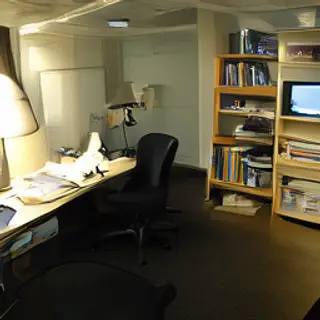 An office workspace with a desk, chair, bookshelf, and lamp 