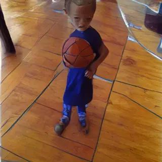 A child holding a basketball, both at correct relative sizes