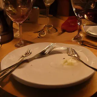 A dinner table scene with a plate, fork, knife, wine glass, 