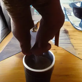 A tiny person standing on the rim of a coffee cup, looking d