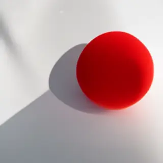 A red sphere on a white surface with a single shadow cast to