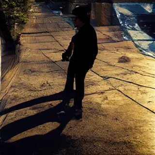 A person standing outdoors at midday with a short shadow dir