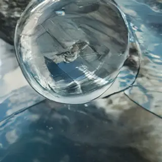 A clear glass sphere sitting on a mirror surface near a pool
