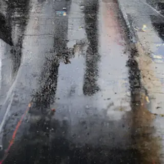 A city skyline reflected in a rain puddle on a street, with 