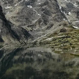 A mountain range reflected in a still alpine lake, with the 