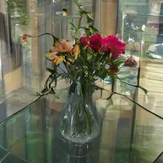 A vase of flowers on a glass table with a clear reflection v