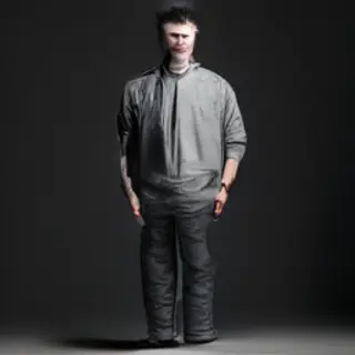 A man standing straight facing the camera, hands in pockets,