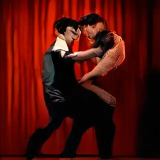 Two tango dancers in a close embrace, the man dipping the wo