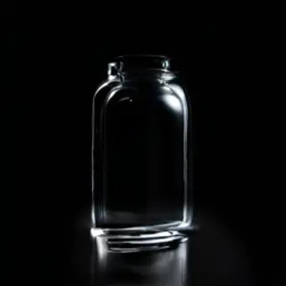 A clear glass perfume bottle on a reflective black surface w