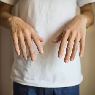 A person standing with both hands visible at their sides, fi