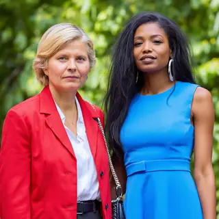Two women standing side by side: one with short blonde hair 