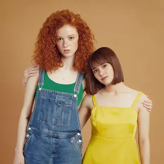 Two friends posing: one tall with curly red hair in denim ov