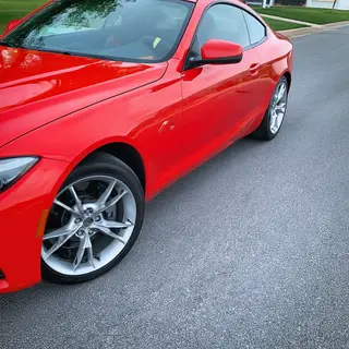A bright red sports car parked on a gray asphalt road — the 