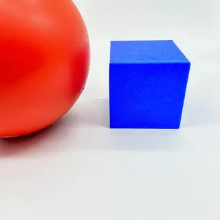 A red ball and a blue cube sitting side by side on a white s