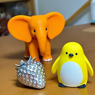 An orange elephant, a yellow penguin, and a silver strawberr