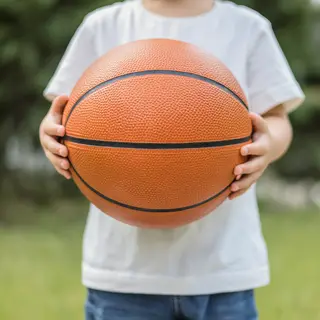 A child holding a basketball, both at correct relative sizes