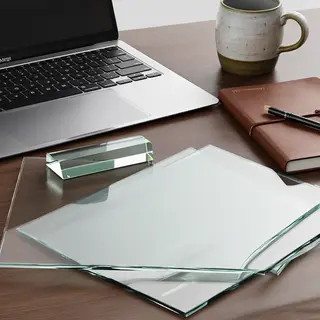 A workspace desk with a brushed aluminum laptop, a leather-b