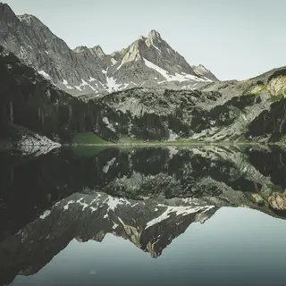 A mountain range reflected in a still alpine lake, with the 